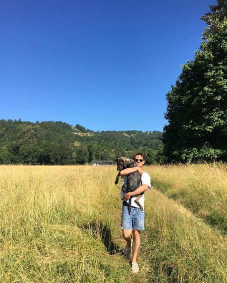Eli Brown in a white shirt holding his dog.